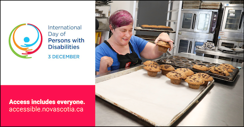 A person with a prosthetic arm arranges muffins on a tray in a kitchen.