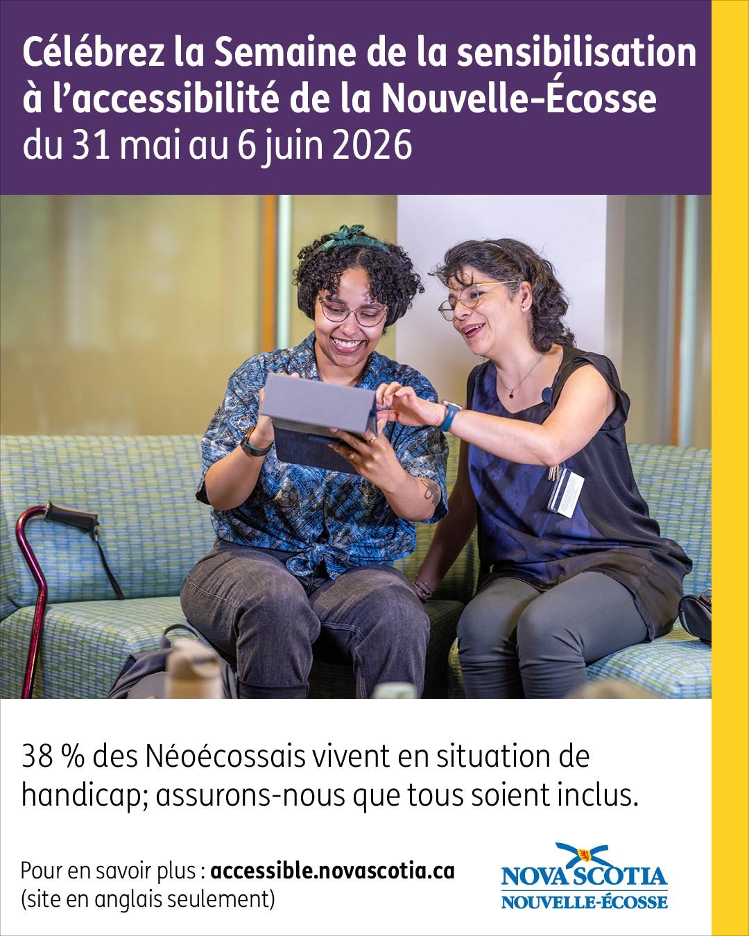 Deux personnes assises sur un canapé, regardant ensemble une tablette, avec une canne de mobilité à côté d'elles.