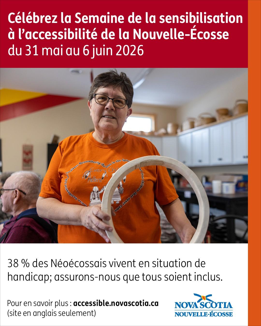 Une personne debout dans une salle communautaire, tenant un cerceau en bois.